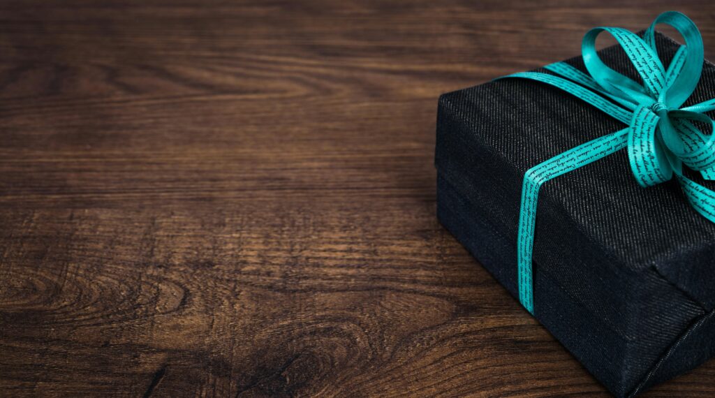 A stylish black gift box with blue ribbon on a wooden table, perfect for celebrations.